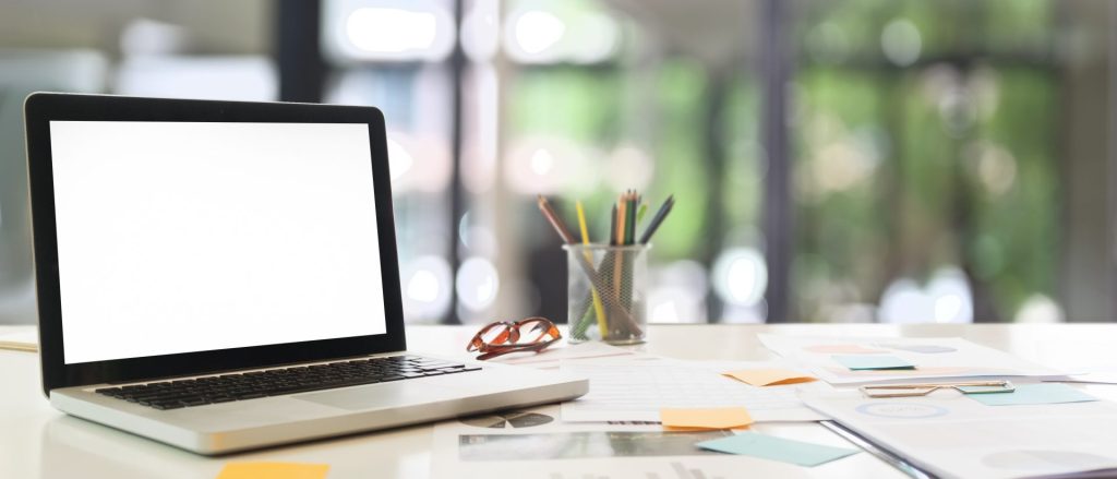 Ein Laptop steht auf einem Holzschreibtisch und zeigt ein einfaches Arbeitsplatz-Setup.