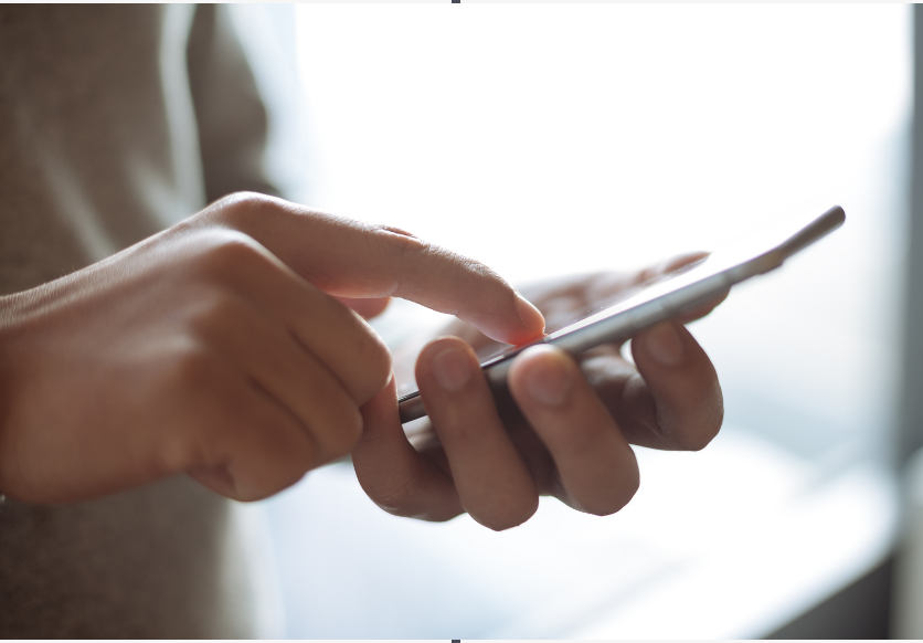 Eine Person hält ein Mobiltelefon, auf dem der Text „So verwenden Sie eine mobile App“ in klarer und gut lesbarer Form angezeigt wird.